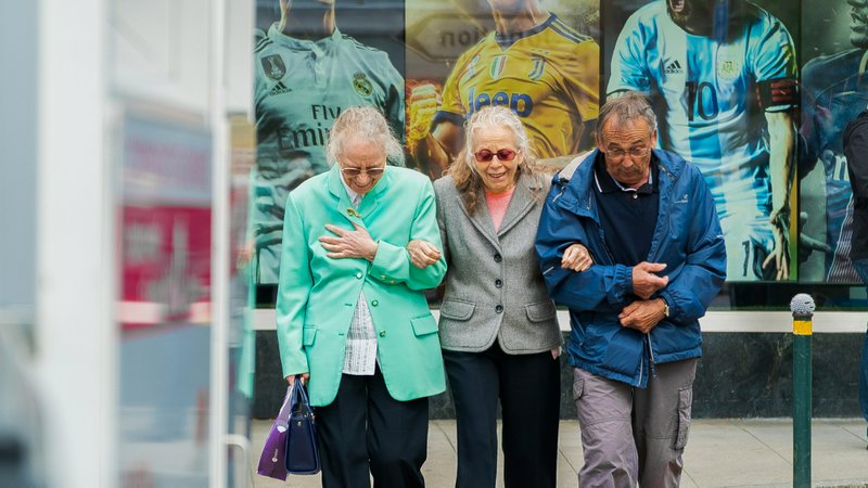 two women and man walking in the street during daytime showcasing the challenges of caregiving for elderly parents.